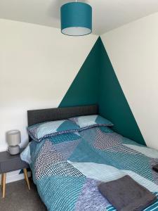 a bedroom with a bed with a green accent wall at 4-6 Guests in centre location with stunning views in Llanberis