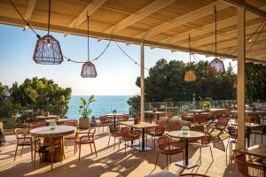 un patio con mesas y sillas y vistas al océano en DALMACIJA PLACES HOTEL by Valamar en Makarska