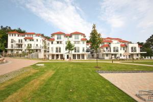 a large white building with red roofs on a lawn at Haus Meeresblick - Ferienwohnung Suedost A 4.05 (Ref. 128720) in Baabe