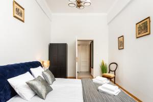 1 dormitorio con 1 cama con sábanas y almohadas blancas en Plac Nowy Apartments - The Heart of Jewish Quarter, en Cracovia