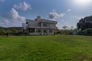 een huis met een groot grasveld ervoor bij SaffronStays Midori, Kolad - private pool villa near river rafting camp in Kolad