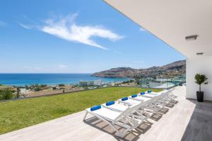 a row of lounge chairs on a patio with the ocean at Villa Kastro in vlicha