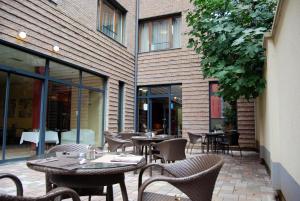 an outdoor patio with tables and chairs and a building at Hotel Regnum Residence in Budapest