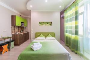 a bedroom with a green bed and a kitchen at Апартаменты Central Park в центре Тюмени in Tyumen