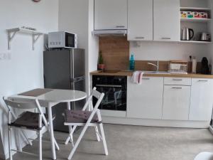 La cuisine est équipée d'une table, de chaises et d'un réfrigérateur. dans l'établissement Studio Cosy Chambray-Les-Tours, à Chambray-lès-Tours