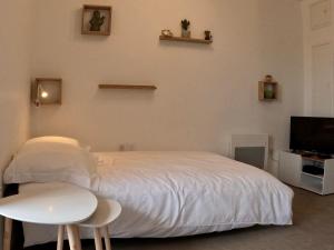 - une chambre avec un lit blanc, une table et une télévision dans l'établissement Studio Cosy Chambray-Les-Tours, à Chambray-lès-Tours