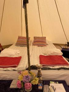 a bed with two pillows and a table with flowers on it at Naturglamping in Kristianstad
