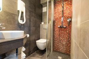 a bathroom with a toilet and a sink and a shower at Hotel Aguado in Dieppe