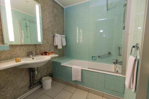 a bathroom with a tub and a sink and a mirror at Hotel Aguado in Dieppe