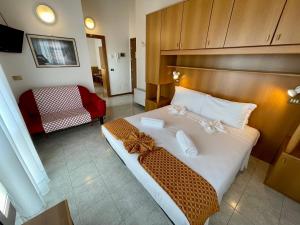 sypialnia z dużym białym łóżkiem z drewnianym zagłówkiem w obiekcie Hotel Rosa Caorle w Caorle