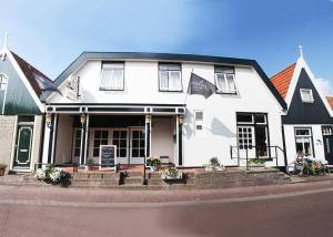 una casa blanca con techo negro en Hotel-Restaurant Loodsmans Welvaren en Den Hoorn