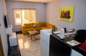 a living room with a yellow couch and a table at Orange Roof Lodge in Abuja