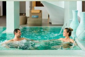 un uomo e una donna che nuotano in una piscina di Longevity Health & Wellness Hotel - Adults Only ad Alvor