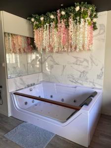 eine Badewanne mit Blumen an der Wand in der Unterkunft Superbe appartement avec Balnéothérapie/spa/ Champagne in Pornic