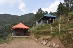 un par de edificios en una colina con una valla en FOREST ACRES CAMPS, en Mukteshwar