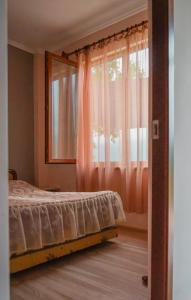 a bedroom with a bed and a window with pink curtains at Ana-Maria Bnb in Tatʼev