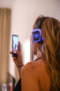 a woman wearing headphones taking a picture with her cell phone at Lloret Vibe Affiliated by FERGUS in Lloret de Mar