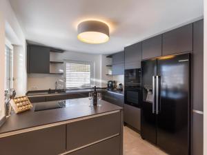a kitchen with black cabinets and a black refrigerator at Sonnberg Living Superior Plus in Brixen im Thale