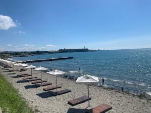 eine Reihe von Sonnenschirmen und Stühlen am Strand in der Unterkunft Beautiful sea view apartment in Midiya Family Grand Resort, Aheloy in Aheloy