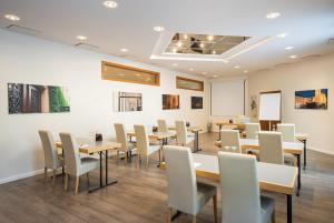 une salle à manger avec des tables et des chaises et un mur blanc dans l'établissement QU Hotel Augsburg, à Augsbourg