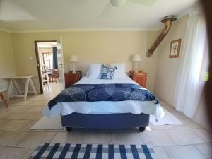 a bedroom with a bed with a blue and white comforter at Wild Hare Cottages in Lions River