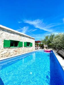 a swimming pool in front of a stone house at Villa Sagosde with Swimming Pool and Mini Golf in Zagvozd