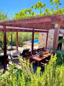 a wooden pergola with a wooden table and chairs at Villa Sagosde with Swimming Pool and Mini Golf in Zagvozd