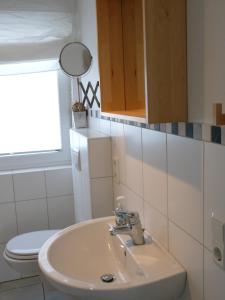 a bathroom with a sink and a toilet at Das GrachtenDOMiZiL Greetsiel in Greetsiel