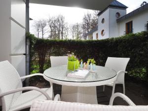 una mesa con sillas y un libro en el patio en Kaiservillen Heringsdorf - Ferienwohnung mit 1 Schlafzimmer und Terrasse D201, en Heringsdorf