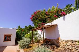 a small white building with flowers on a wall at Villa Geckos Charming holiday finca 5 min by car to the fabulous Cala Salada beach in San Antonio