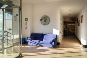 a living room with a blue couch and a clock at Alda Route 42 in Illescas