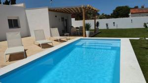 basen z dwoma krzesłami i dom w obiekcie PALAPA GARDEN alojamientos, piscina privada y cerca del mar w mieście Chiclana de la Frontera