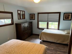 a bedroom with two beds and a dresser and two windows at Echo Valley Cottages in Coolbaugh