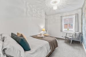 a bedroom with a bed and a chair and a window at Silver Stag Properties, Modern 2 BR House in Thringstone