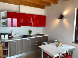 eine Küche mit roten Schränken und einem weißen Tisch in der Unterkunft La Quiete 56 Lake view Apartment by Gardadomusmea in Tremosine sul Garda