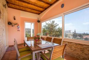 une salle à manger avec une table, des chaises et une grande fenêtre dans l'établissement Irene Villa, à Psinthos