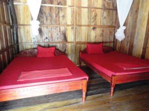 two beds in a wooden room with red sheets at Sea House Guest House in Koh Rong Island
