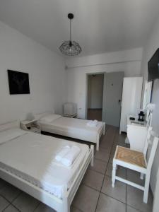 pokój z 2 łóżkami i krzesłem w obiekcie Sofia w mieście Tinos