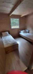 Duas camas num pequeno quarto com uma janela em Agroturystyka SABAT em Imielno