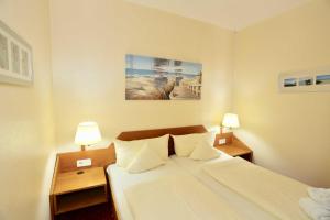 a hotel room with a bed and two lamps on tables at Inselresidenz Strandburg - Ferienwohnung 303 (Ref. 50971) in Juist +9 photos