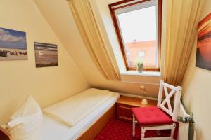 ユイストにあるInselresidenz Strandburg - Ferienwohnung 303 (Ref. 50971)のベッド1台と赤い椅子が備わる小さな客室です。