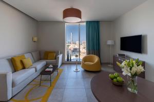 شقق اداجيو الفندقية في جدة: غرفة معيشة مع أريكة وتلفزيون