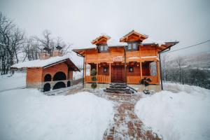 a large wooden house with snow on the ground at Vila Rudnicka Idila in Gornji Milanovac