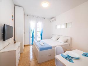 1 dormitorio con cama, mesa y TV en Apartments Prkačin en Starigrad-Paklenica
