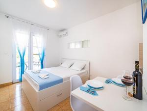 Habitación blanca con cama y mesa con una copa de vino en Apartments Prkačin en Starigrad-Paklenica