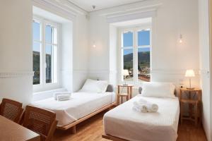 two beds in a room with two windows at Galaxidaki 1857 guesthouse in Galaxidhion