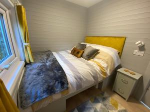 a bedroom with a bed with a yellow headboard and a window at The Beehive -Stunning Views - Hot Tub - Romantic in Launceston