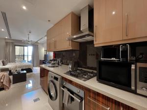 a kitchen with a stove and a microwave at Trophy - Sky High Haven Suite in Dubai