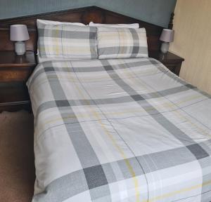 a bed with a plaid blanket and two pillows at Queensberry Arms Hotel in Annan