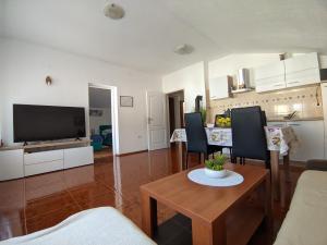 sala de estar con TV, mesa y sillas en Apartments Darko, en Rovinj